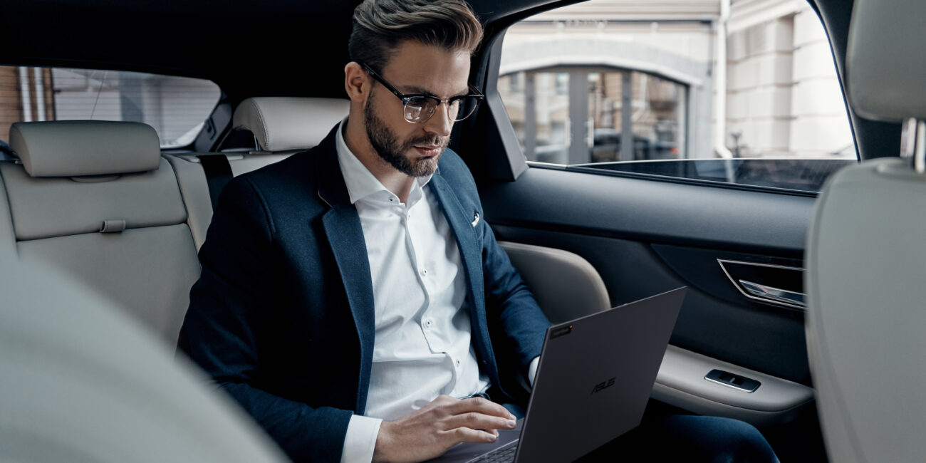 Full concentration at work. Confident young man in full suit working using laptop while sitting in the car; Shutterstock ID 1005625339; purchase_order: -; job: -; client: -; other: -